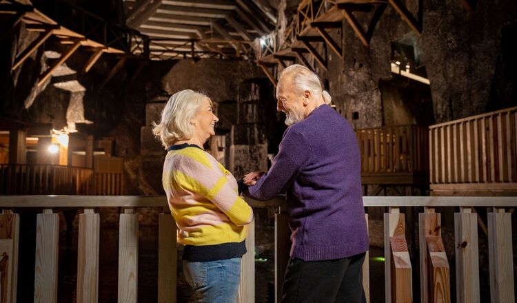 Uzdrowisko Kopalnia Soli Wieliczka Starsza para seniorów rozmawiająca na tle zabytkowej kopalni soli Wieliczka z drewnianymi konstrukcjami